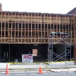 Workers remove the old glass storefront windows and install wall studs in preparation to give the building a traditional brick front facade. 