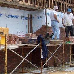 Workers start laying the brick for the front facade of the building.